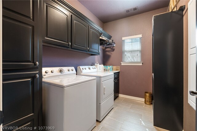 laundry area featuring washing machine and clothes dryer and cabinets