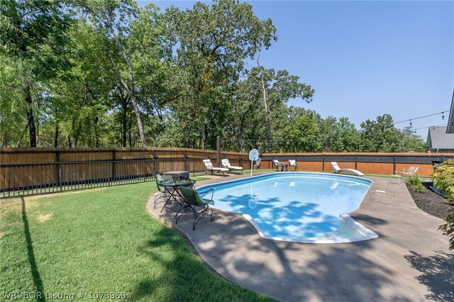 view of swimming pool featuring a lawn, a diving board, and a patio