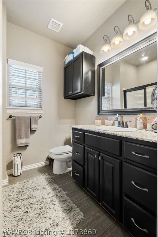 bathroom with vanity, toilet, and wood-type flooring