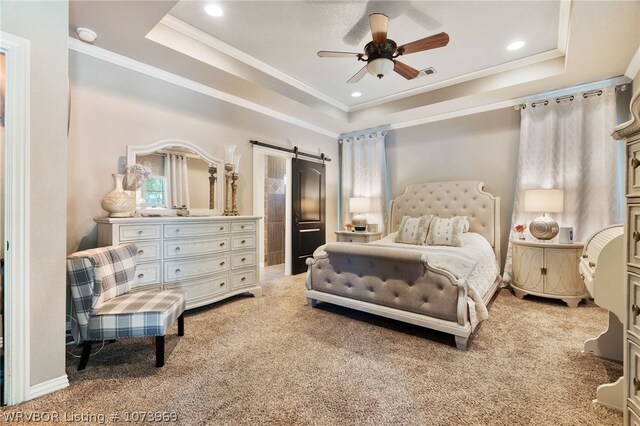 bedroom featuring a raised ceiling, ceiling fan, a barn door, ornamental molding, and carpet floors