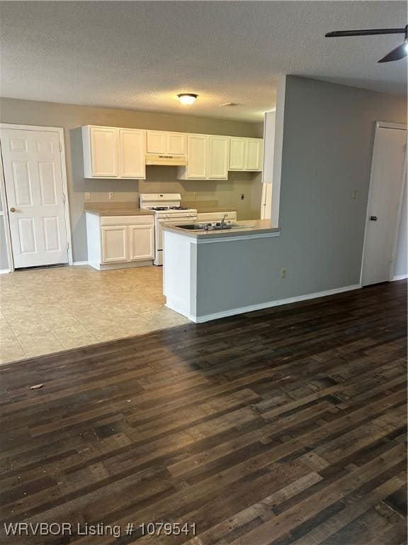 kitchen with under cabinet range hood, a textured ceiling, white gas range, and dark wood finished floors