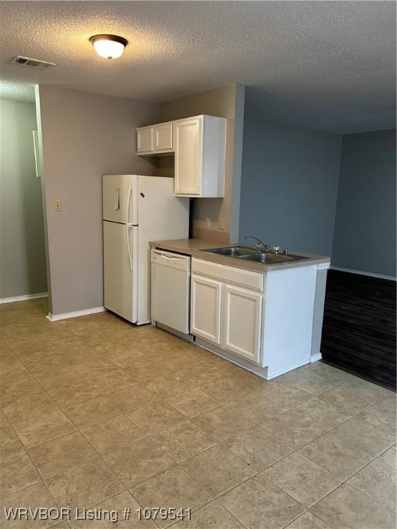 kitchen with white appliances, visible vents, a peninsula, a sink, and white cabinetry