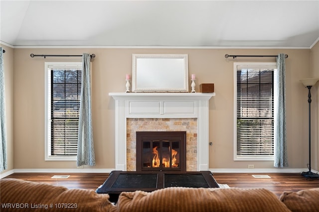 unfurnished living room with lofted ceiling, plenty of natural light, visible vents, and a glass covered fireplace