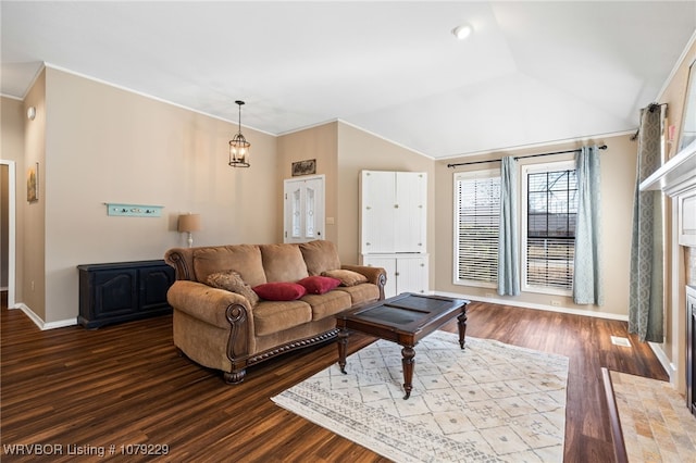 living room featuring a fireplace with flush hearth, lofted ceiling, ornamental molding, and wood finished floors