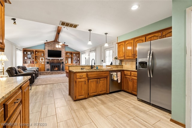 kitchen with stainless steel appliances, visible vents, open floor plan, a sink, and a peninsula