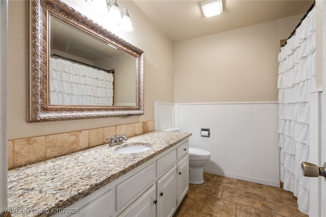 bathroom with wainscoting, vanity, and toilet