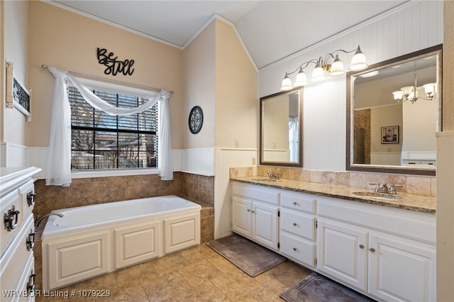 bathroom featuring double vanity, wainscoting, a sink, an inviting chandelier, and a bath