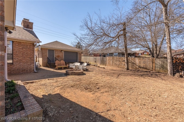 view of yard with a garage, a fenced backyard, and an outbuilding