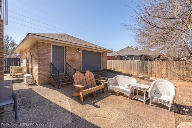 view of patio / terrace with entry steps, an outdoor structure, fence, and an attached garage