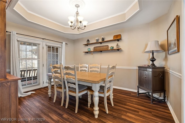 dining area featuring a tray ceiling, dark wood-style flooring, a notable chandelier, and baseboards