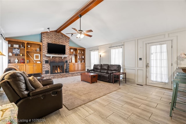 living area featuring lofted ceiling with beams, ceiling fan, wood tiled floor, a fireplace, and a decorative wall