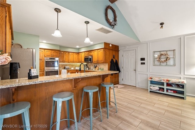 kitchen with appliances with stainless steel finishes, backsplash, brown cabinets, and a decorative wall