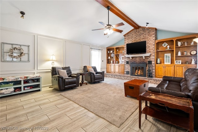 living room with vaulted ceiling with beams, ceiling fan, a decorative wall, wood finish floors, and a fireplace