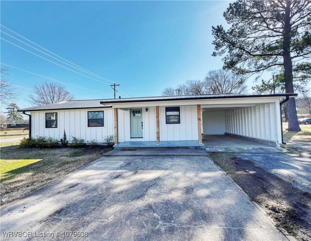 view of front facade with metal roof, a carport, board and batten siding, and driveway