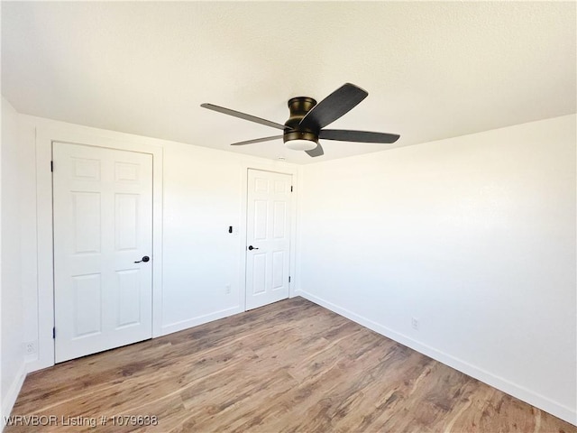 unfurnished bedroom featuring wood finished floors, baseboards, and ceiling fan