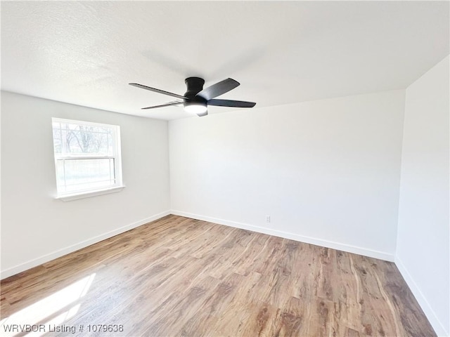 spare room with a ceiling fan, wood finished floors, baseboards, and a textured ceiling