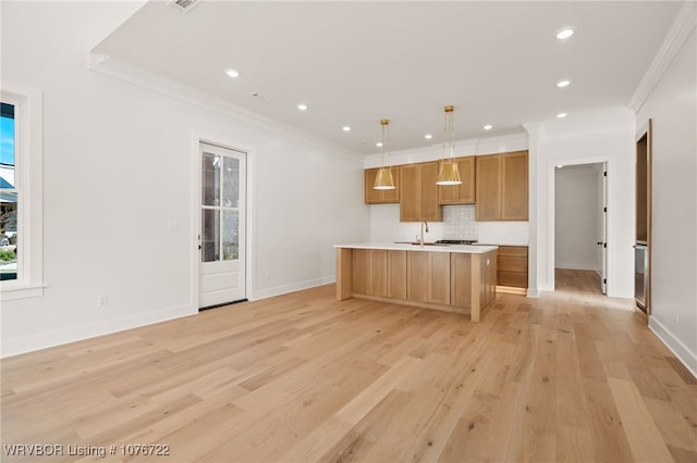 kitchen featuring backsplash, light wood-type flooring, hanging light fixtures, and a kitchen island with sink