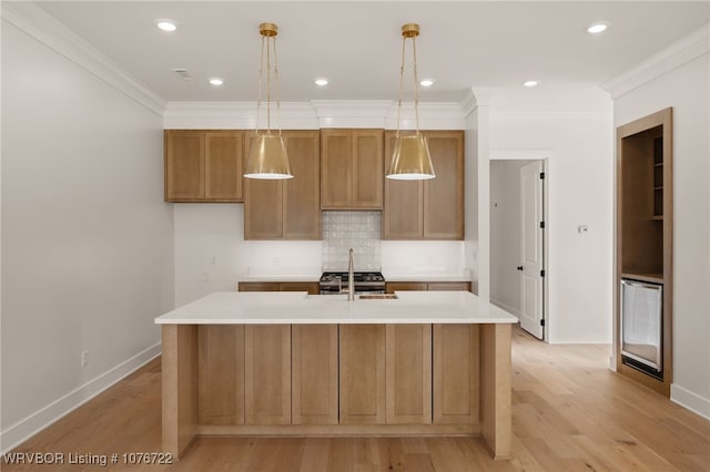 kitchen with decorative light fixtures, decorative backsplash, a kitchen island with sink, and ornamental molding