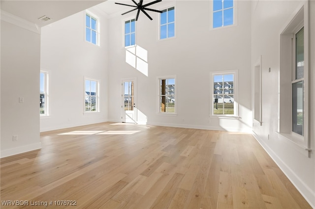 unfurnished living room with crown molding, ceiling fan, light hardwood / wood-style floors, and a high ceiling