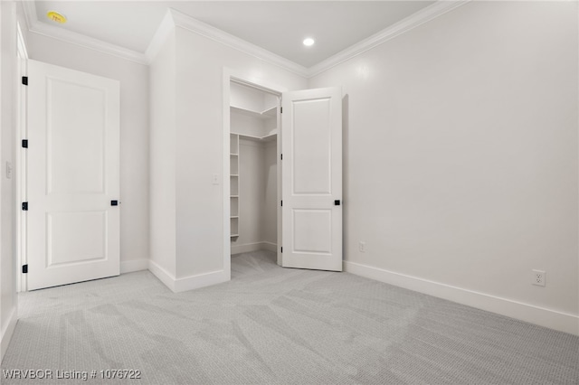 unfurnished bedroom featuring crown molding, a closet, light colored carpet, and a spacious closet