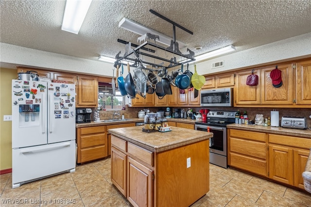 461510 E 1130th Rd, Sallisaw, OK 74955 - kitchen with appliances with stainless steel finishes, a textured ceiling, a sink, a kitchen island, and light tile patterned floors
