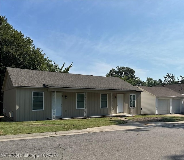 ranch-style house with a porch, a garage, an outbuilding, and a front lawn