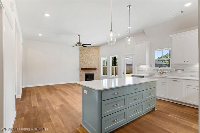 kitchen featuring pendant lighting, a center island, white cabinets, decorative backsplash, and light wood-type flooring