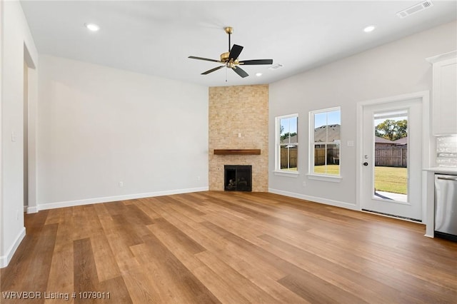 unfurnished living room featuring ceiling fan, a stone fireplace, and light hardwood / wood-style flooring