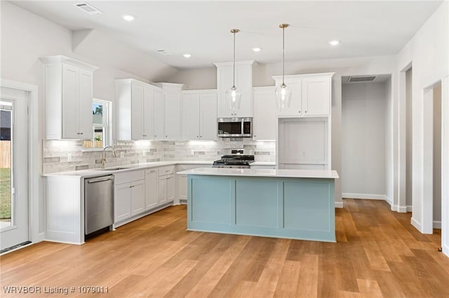 kitchen featuring appliances with stainless steel finishes, a center island, pendant lighting, and white cabinets