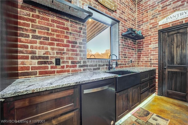 kitchen featuring light stone countertops, dishwasher, sink, brick wall, and dark brown cabinets