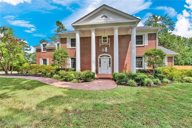 neoclassical home with a front lawn and brick siding