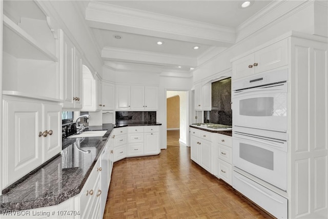 kitchen with sink, white cabinets, beamed ceiling, decorative backsplash, and double oven