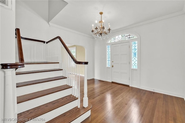 foyer entrance with a notable chandelier, dark hardwood / wood-style flooring, and crown molding