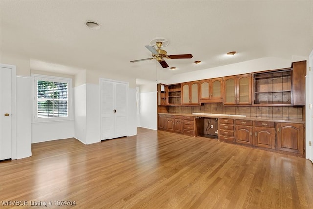 kitchen featuring ceiling fan, built in desk, light hardwood / wood-style floors, and tasteful backsplash