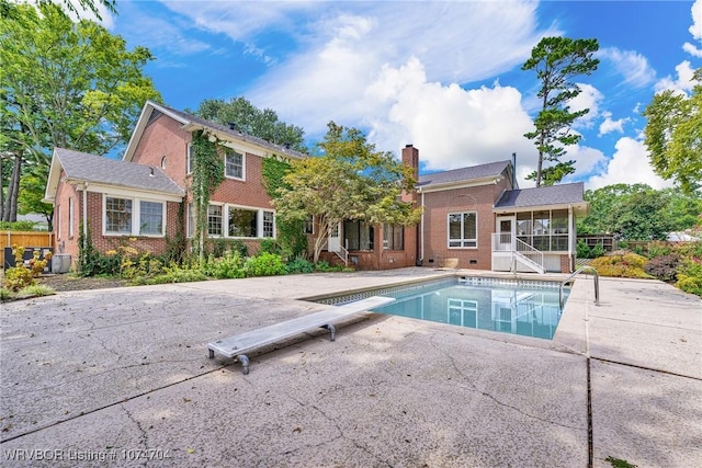 view of swimming pool featuring a patio, a diving board, and a sunroom