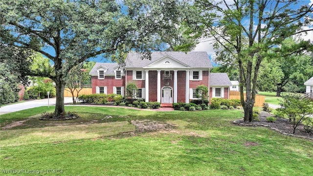 neoclassical home featuring a front lawn and brick siding