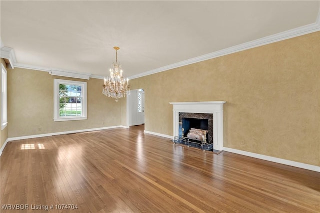 unfurnished living room featuring wood-type flooring, a premium fireplace, an inviting chandelier, and crown molding