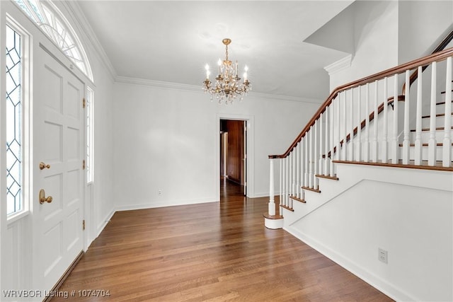 entryway featuring wood-type flooring, a chandelier, a healthy amount of sunlight, and crown molding