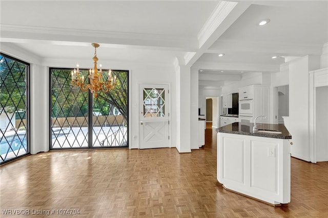 interior space featuring decorative light fixtures, beam ceiling, plenty of natural light, and sink