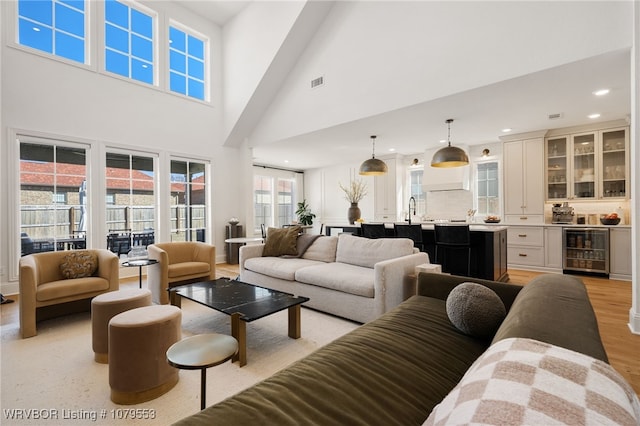 living area featuring wine cooler, visible vents, recessed lighting, and light wood-style floors