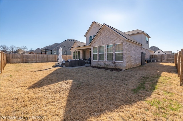 back of property featuring a patio, a yard, a fenced backyard, outdoor lounge area, and brick siding