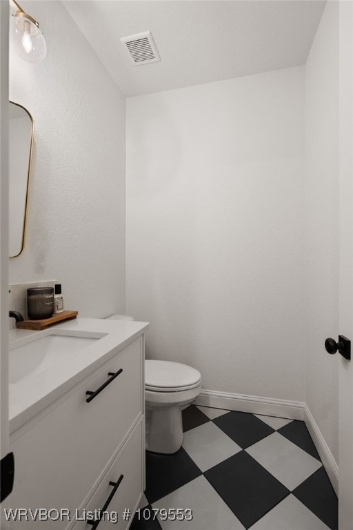 bathroom featuring visible vents, baseboards, toilet, tile patterned floors, and vanity