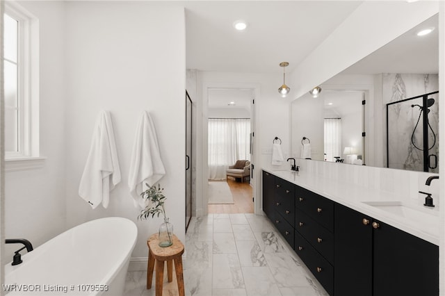 full bath featuring a sink, marble finish floor, a shower stall, and double vanity