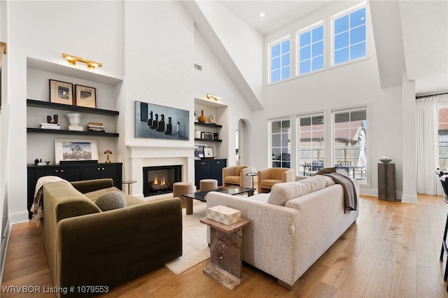 living area with visible vents, baseboards, built in features, a fireplace, and wood-type flooring