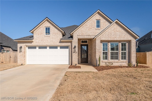 view of front of house with an attached garage, fence, brick siding, and driveway