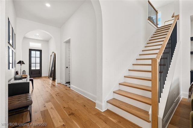 foyer with hardwood / wood-style floors, stairway, baseboards, recessed lighting, and arched walkways