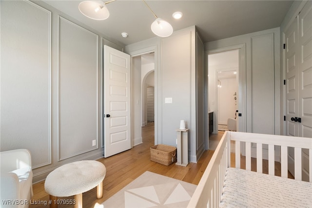 bedroom featuring light wood-style flooring and arched walkways