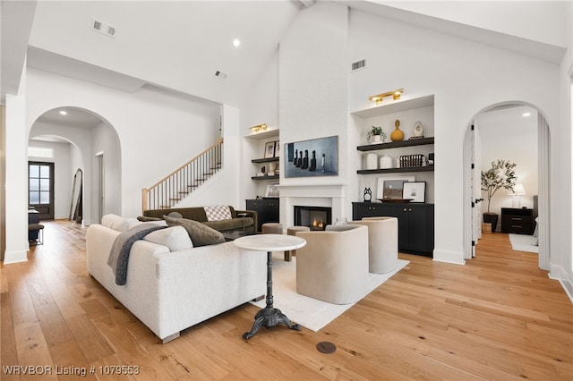 living area with visible vents, arched walkways, and light wood finished floors