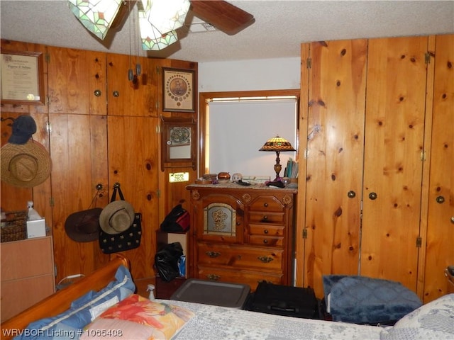 bedroom featuring wooden walls and a textured ceiling