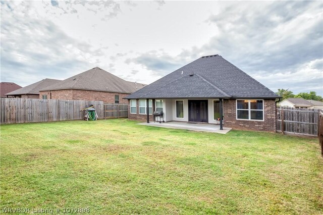 rear view of house featuring a yard and a patio